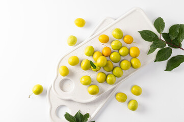 yellow freshly torn cherry plum with leaves on a white background, top view