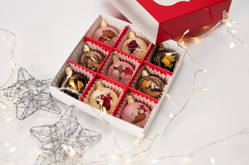 Box of festive new year handmade chocolate, christmas holidays gift on white background with garland and stars made of wire