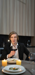 Alone man at home festive valentine's day dinner, drinking alcohol red wine in the evening over dinner, romantic date online