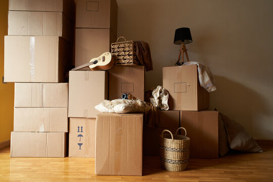 Background image of cardboard boxes stacked in empty room with personal belongings inside, moving or relocation concept, copy space