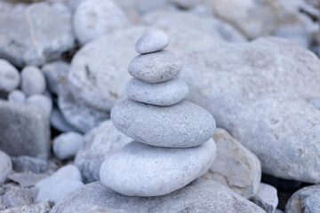 Fototapeta na wymiar Stack balancing pebble stones pool with out of focus for background. Balanced rocks on the edge of a lagoon