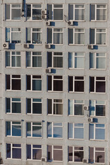 Office building with lots of windows close-up. There are many air conditioners on the facade of the building.