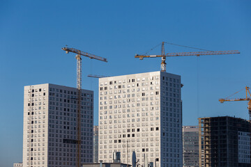 Fototapeta premium Construction of a multi-storey building. A high-rise crane on the construction of a multi-storey building.