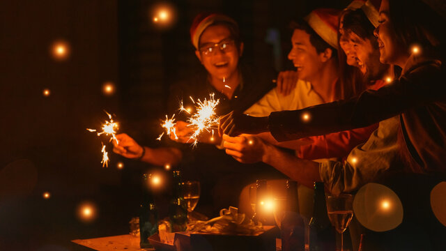 Happy multiracial people in party holding sparklers and champagne glasses celebrating New year eve together, excited diverse young friends having fun enjoying celebration together.
