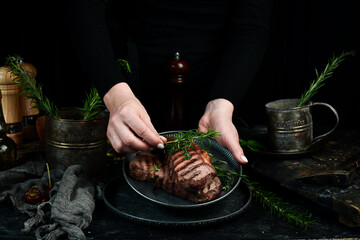 Two grilled ribeye beef steak on a plate in the hands of the chef. Food banner. On a black...