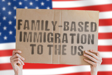 The phrase " Family-based immigration to the US " on a banner in men's hand with blurred American flag on the background. Visa. Immigrate. Naturalization. Spend time. accommodation. Passage. Change
