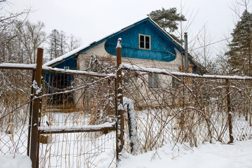 Old village house behind a fence on a winter snowy day