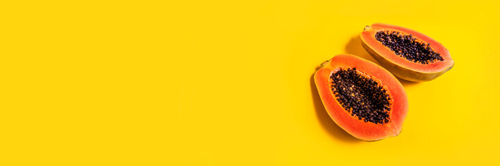 Fresh two halves of papaya on yellow background, top view. Banner. Space for text