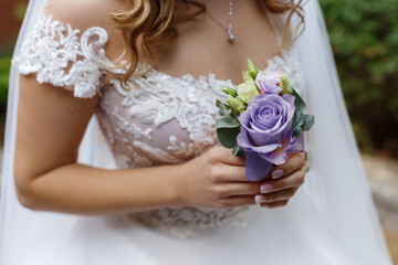 Bride holding in his hands a boutonniere vith rose of Very Peri colour. Trendy color of the year 2022 in weddings flowers. 