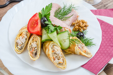 Crepes stuffed with ham garnished with herbs on a white plate