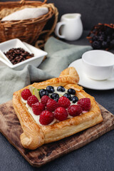 Sweet raspberry and cream, puff pastry dessert, diamond shaped. Empty white coffee cup on background
