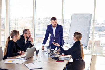 Business people working together in a modern office with cityscape view. The director tells the staff about new technologies. Office work concept