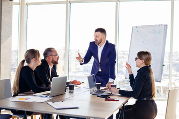 Business people working together in a modern office with cityscape view. The director tells the staff about new technologies. Office work concept