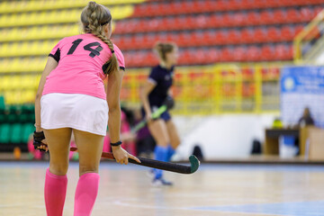 Young girl hockey player playing indoor hockey. Image of female player with stick with copy space
