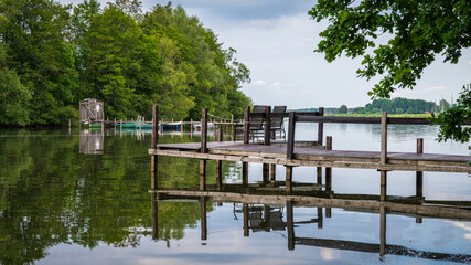 Obraz premium A jetty with two chairs at the shore of the Steinhuder Meer with a view at the bathing island in Steinhude, Lower Saxony, Germany