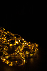 Christmas decor. Illumination for the New Year. Glowing garland on a black background. Festive background. Christmas background. Golden threads. Postcard in luxury style.
