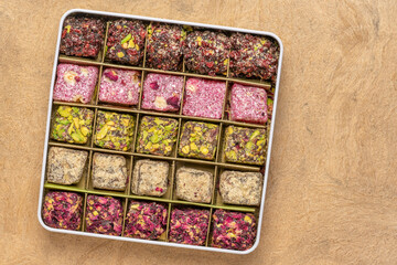 assortment of traditional Turkish delight (lokum) in a tin box against handmade paper with a copy...