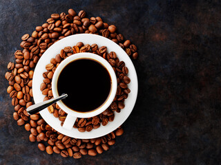 Cup of coffee on a saucer and roasted coffee beans. Black coffee in ceramic cup on a dark background. Food background. Top view. Copy space