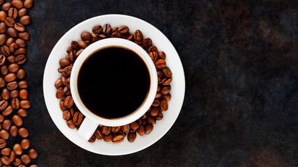 Cup of coffee on a saucer and roasted coffee beans. Black coffee in ceramic cup on a dark background. Food background. Top view. Copy space