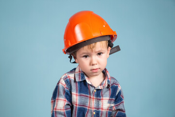 Serious little kid boy engineer or architect in a protective orange helmet