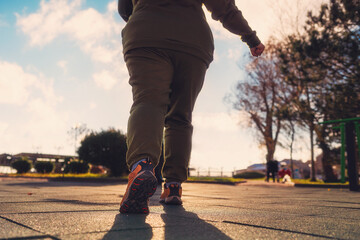 A overweight woman in sports clothes, standing ready to run. Legs close-up. Low angle view. The...