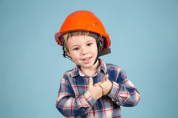 Funny boy engineer or architect in a protective orange helmet showing thumb up.