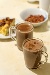 Hot cocoa or chocolate drink in glass mug on wooden table. Concept of cosy Christmas and New Year holidays, copy space