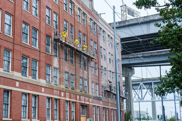 Window cleaners and pressure washers working on side of Building