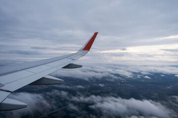 Fototapeta na wymiar Classic image through aircraft window onto wing. Flight view over clouds