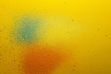 Multicolored powder, orange, green and yellow, scattered on a bright background. Copy space. Abstract texture. Top view. 
