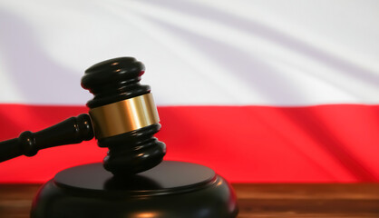 Closeup of isolated judge wood gavel with blurred polish flag background (focus on hammer head)