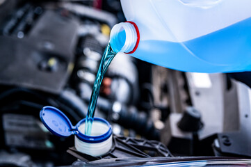 Pouring antifreeze. Filling a windshield washer tank with an antifreeze in winter cold weather... - obrazy, fototapety, plakaty