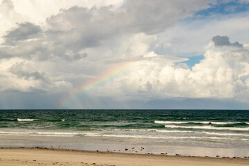A Rainbow over the ocean, seen from the beach. 