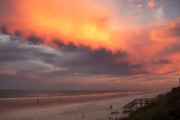 Brilliant red sky at sunset on a cloudy beach.
