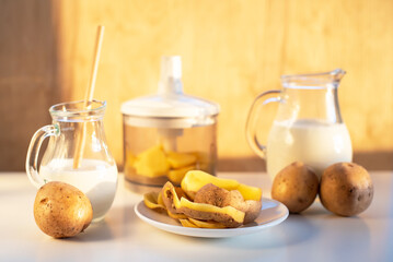 Vegan plant milk from potato in glass jar and potato tubers on the table. Concept of potato milk, vegan sustainable option, plant-based dairy. Substitute drink, healthy eating, diet, nutrition