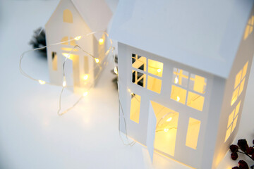 Childrens crafts made of white paper for Christmas, New Year. The decor of the houses is made of cardboard and garlands. Cozy atmosphere.