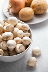 Ingredients for mushroom cream soup on grey table. Champignon, potatoes, onions. Top view.