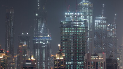 Plakat High multi-storey buildings under construction and cranes at night timelapse