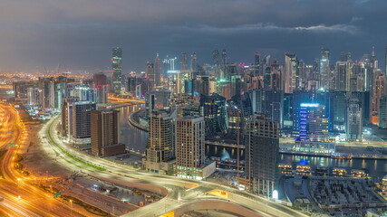 Fototapeta premium Skyline with modern architecture of Dubai business bay towers night to day timelapse. Aerial view