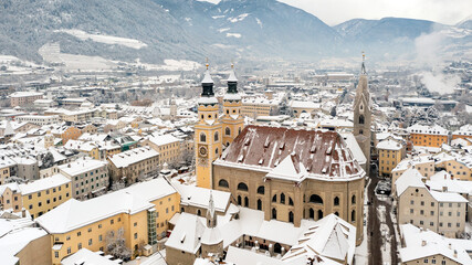 Cathedral of Santa Maria Assunta and San Cassiano in Bressanone. Brixen, is a little town in South Tirol in northern Italy. Aerial view of the old center city covered with snow in winter time. - obrazy, fototapety, plakaty