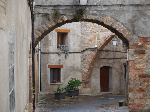 arco de medio punto adovelado de piedra color marrón con un farol en la parte superior, al fondo un arco ojival, en pueblo medieval de arén, huesca, aragón, españa, europa