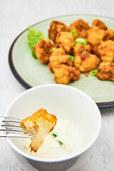Vegan cauliflower buffalo wings on a fork. Tasty vegetarian food close up. crispy fried cauliflower bites