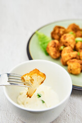 Vegan cauliflower buffalo wings on a fork. Tasty vegetarian food close up. crispy fried cauliflower bites
