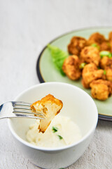 Vegan cauliflower buffalo wings on a fork. Tasty vegetarian food close up. crispy fried cauliflower bites