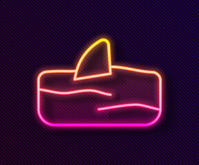 Glowing neon line Shark fin in ocean wave icon isolated on black background. Vector