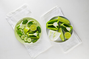 Sliced green vegetables and fruits on plates. Green diet food on white background. Healthy and vegetarian food. Top view