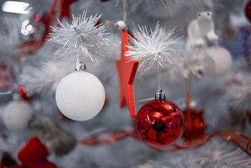 Beautiful Christmas red and silver balls on a white Christmas tree with decorations in the form of ribbons with the inscriptions Merry Christmas and Happy New Year