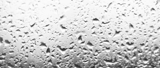 Water drops behind glass. Background from raindrops on the window. Black-and-white backdrop made of drips of water. Creative pattern