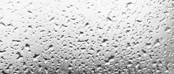 Water drops behind glass. Background from raindrops on the window. Black-and-white backdrop made of drips of water. Creative pattern