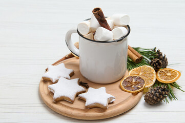 Food composition with white mug with hot chocolate, cinnamon stick and marshmallows on a round wooden board with baked gingerbread cookies sprinkled with sugar powder. Christmas food background